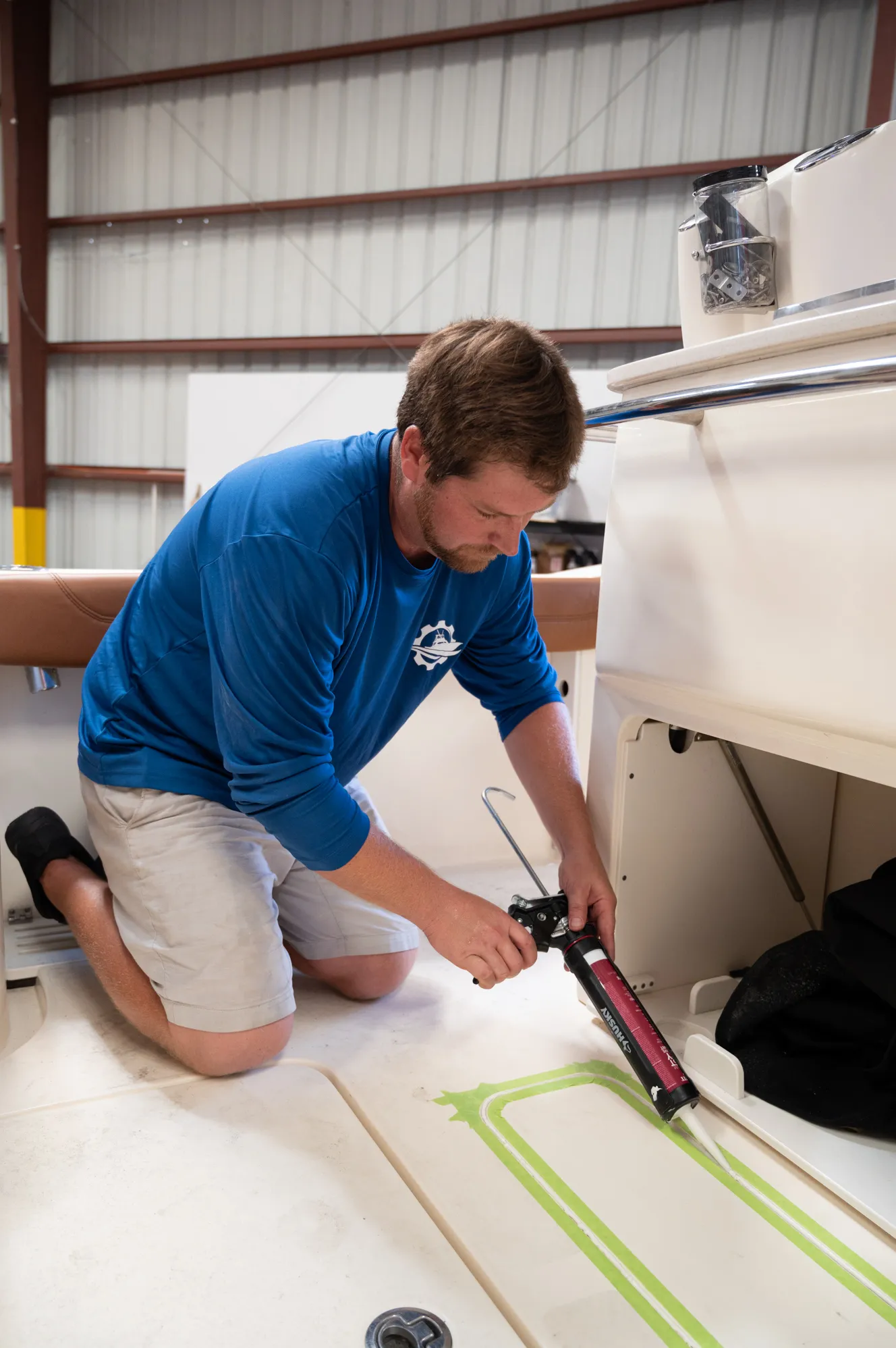Applying sealant along a hull seam in the shop