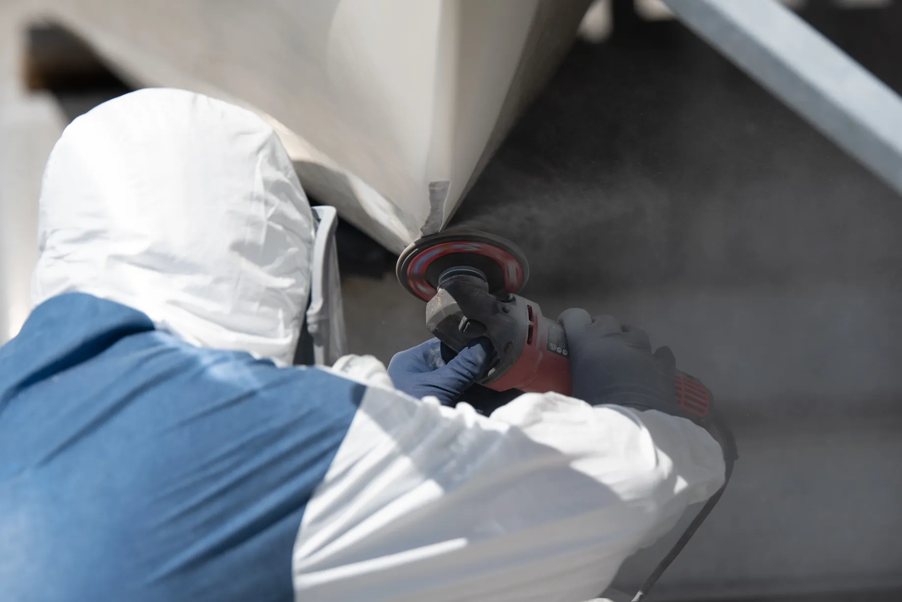 Technician grinding fiberglass with a cloud of dust