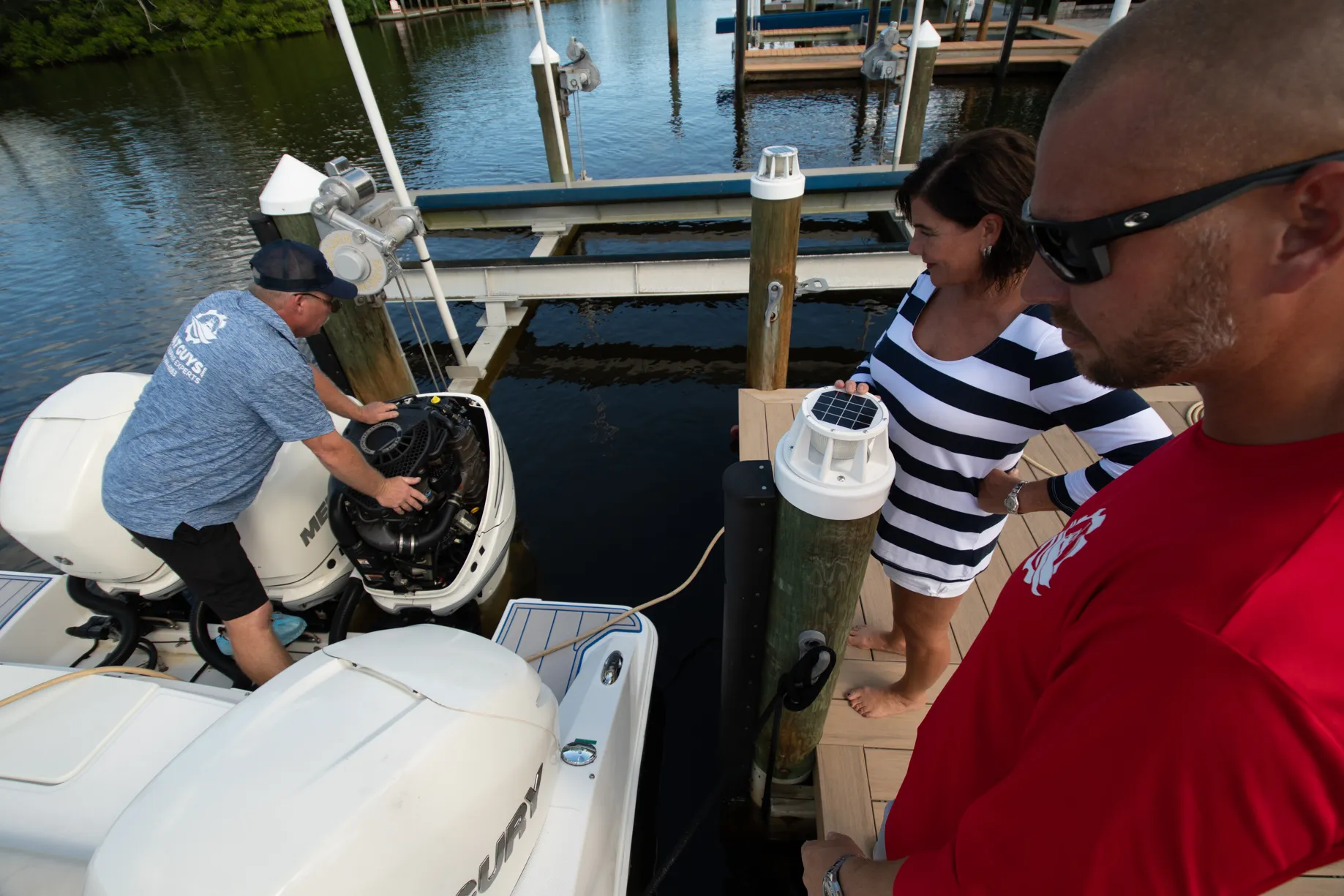Technician opening up a Mercury outboard while the customer watches