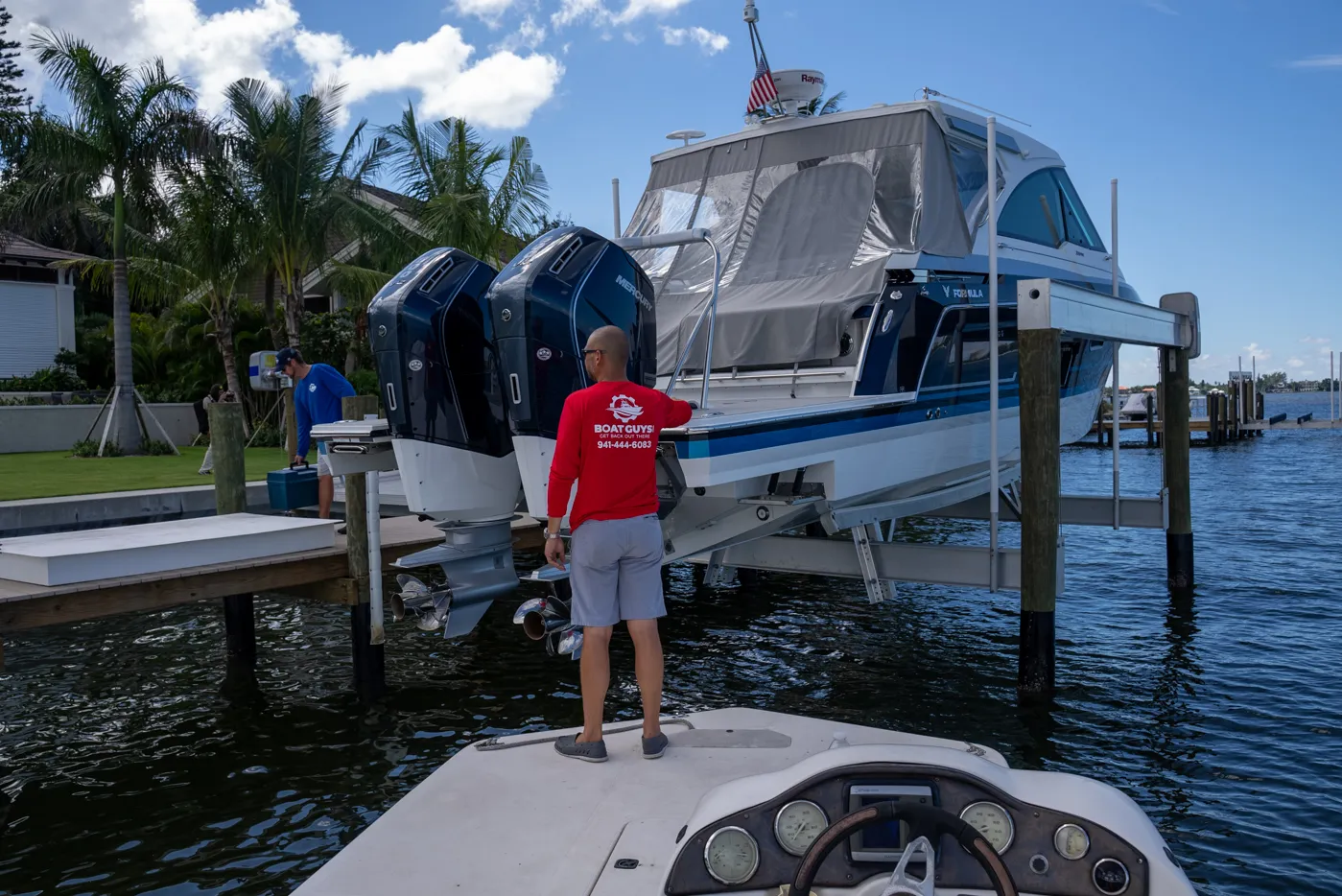 Boat Guys technician at the dock beside a twin-outboard cruiser