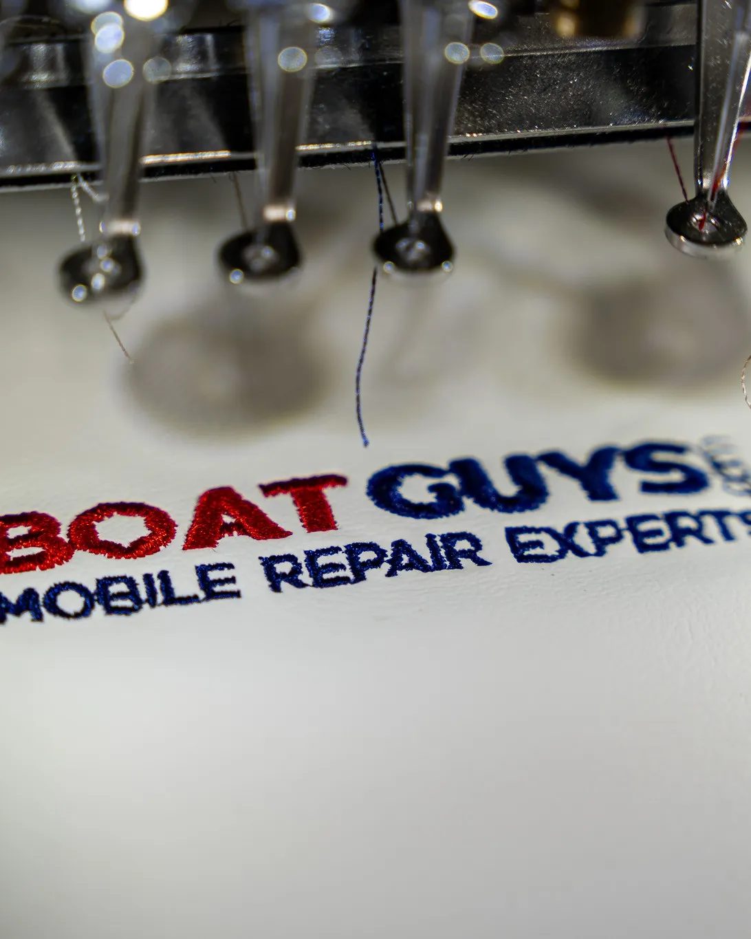Embroidery machine stitching the Boat Guys logo onto marine upholstery