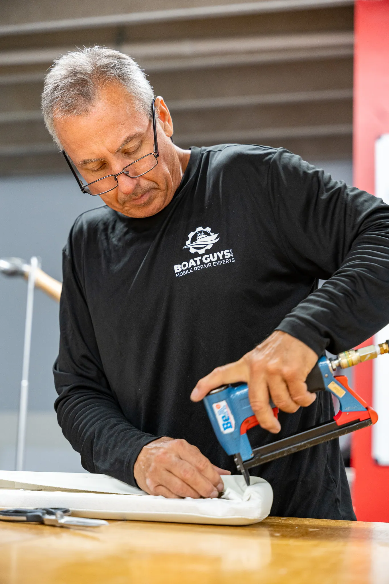 Boat Guys upholsterer stapling a freshly covered boat cushion